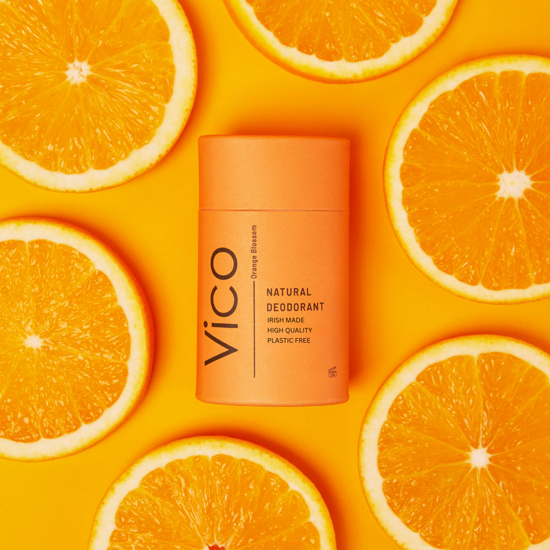 Natural deodorant with sandalwood, patchouli, lavender, and wooden sticks on a peach background.