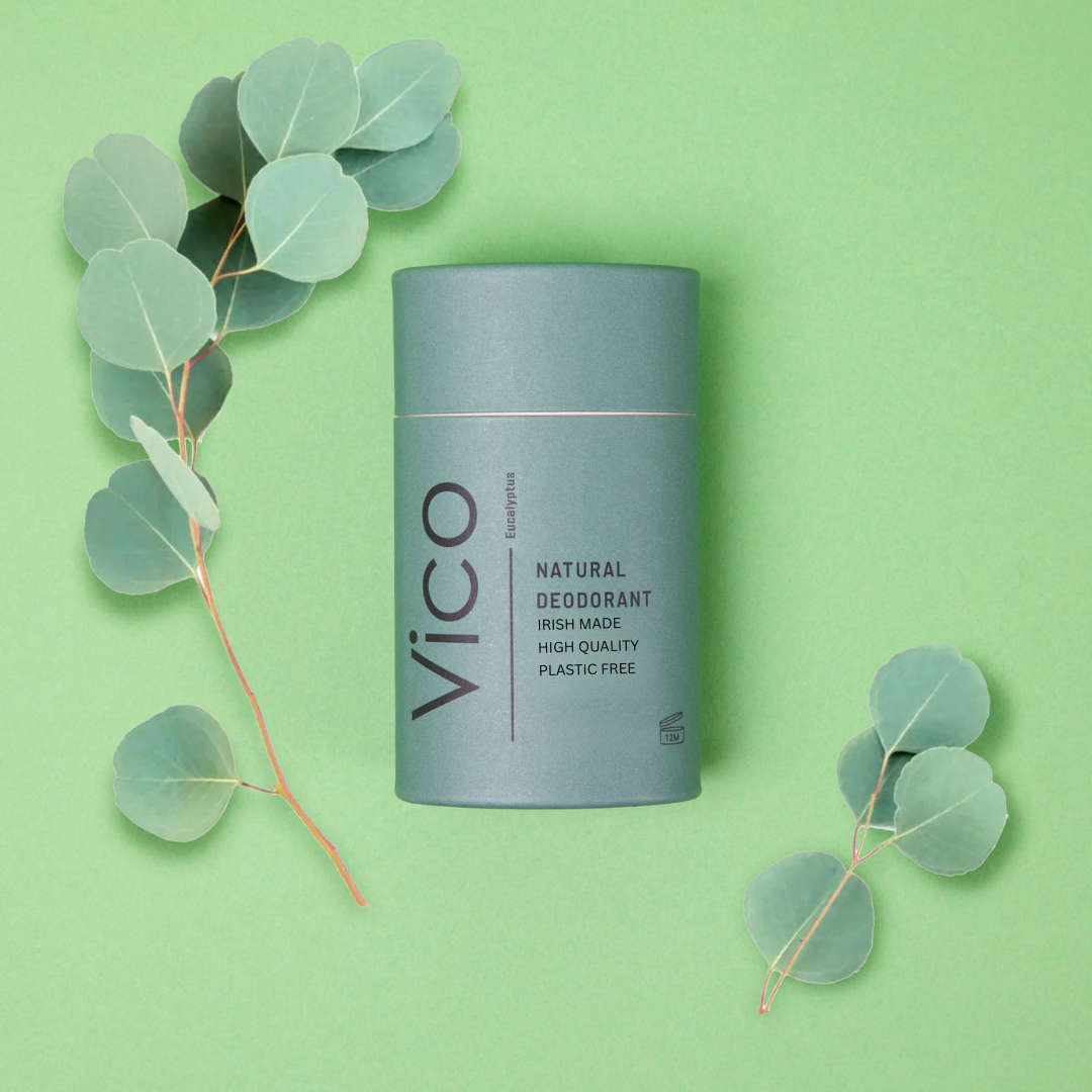 Natural deodorant package with eucalyptus leaves on a green background.
